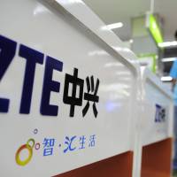 A sales clerk stands at counters selling mobile phones produced by ZTE Corp. at an appliance store in Wuhan in central China\'s Hubei province, in 2012. ZTE, a Chinese tech giant, was brought to its knees and delayed shipments of imported U.S. cars, apples, lumber and other agricultural products are the early casualties as China and the U.S. exchange salvos in a trade dispute. | CHINATOPIX / VIA AP