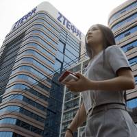 A woman pass by a ZTE building in Beijing May 8. President Donald Trump\'s weekend social media musings about China injected new uncertainty into Washington\'s punishment of Chinese tech giant ZTE and planned trade talks between the two countries. | AP
