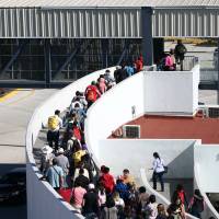 Members of a caravan of migrants from Central America enter the U.S. border and customs facility in Tijuana, Mexico, on Friday. | REUTERS