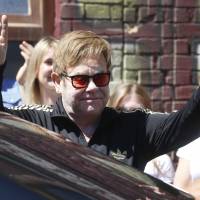 Elton John gestures to fans as he leaves a city market in Kiev Monday. John is in the Ukrainian capital for work on his AIDS foundation charity. | AP