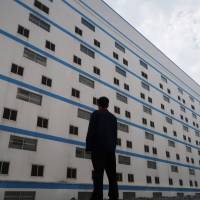 A worker poses outside a seven-story pig building of Guangxi Yangxiang\'s farm at Yaji Mountain Forest Park in Guangxi province, China, March 21. | REUTERS