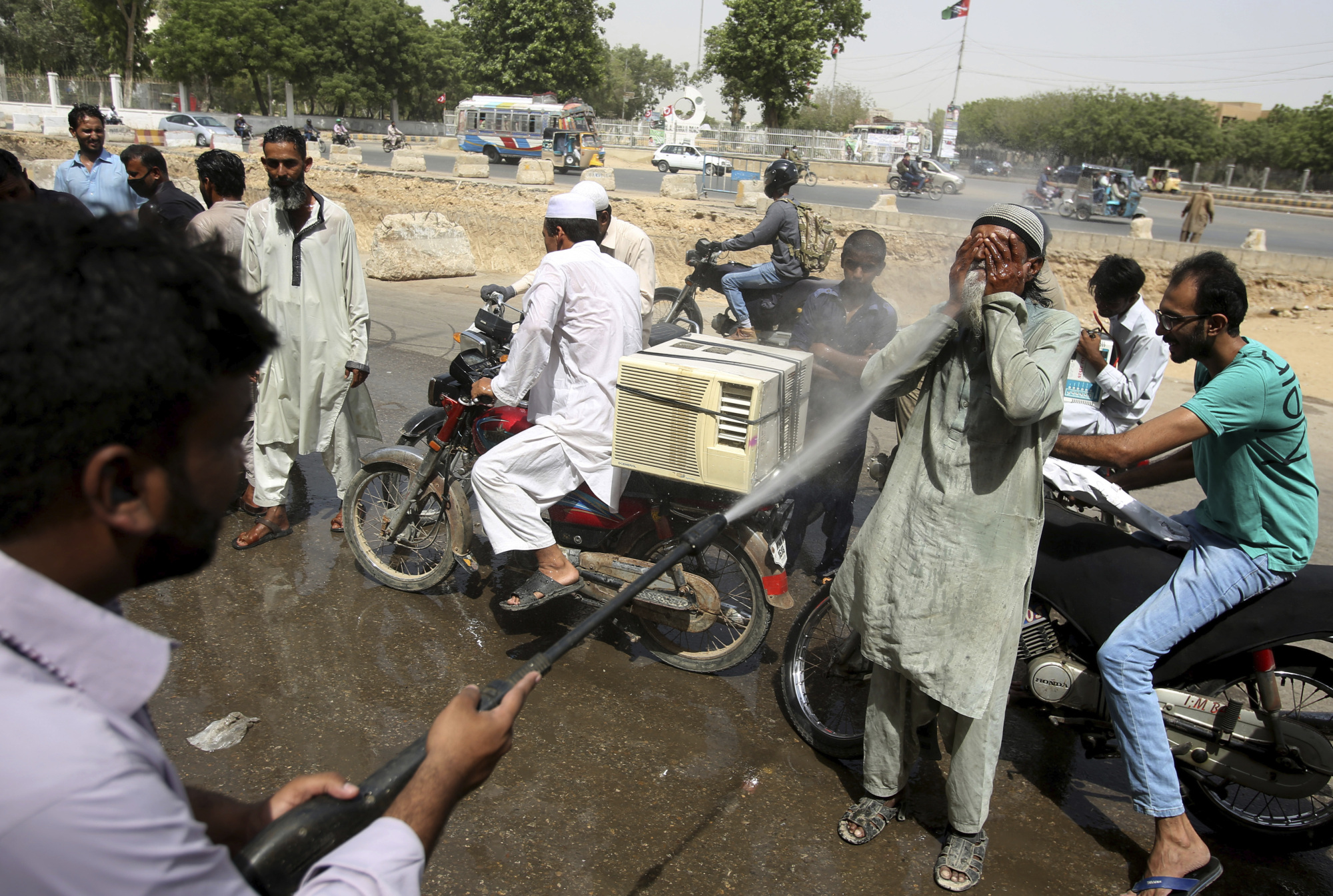 Pakistani volunteers spray water on people to keep them cool as temperatures reached 43 Celsius (109.4 Fahrenheit) in Karachi, Pakistan, Monday. The Meteorological Department has issued a heat-wave alert for three days. | AP