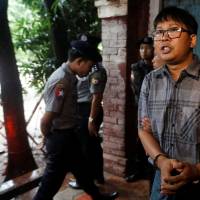 Detained Reuters journalist Wa Lone is escorted by police after a court hearing in Yangon Monday. | REUTERS