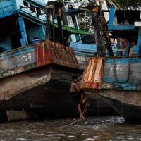 A boy climbs up on a fishing boat anchored on the bank of the Yangon River in Yangon on May 21. | AFP-JIJI