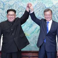 North Korean leader Kim Jong Un (left) and South Korean President Moon Jae-in raise their hands after signing on a joint statement at the border village of Panmunjom in the Demilitarized Zone in South Korea on April 27. | AP