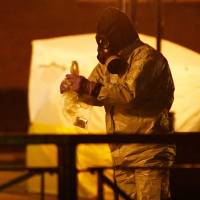 Members of the emergency services wearing protective clothing work near the bench where former Russian intelligence officer Sergei Skripal and his daughter, Yulia, were found poisoned in Salisbury, Britain, March 13. | REUTERS