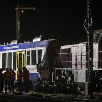 Firefighters and rescuers work at the scene where two trains collided late Monday in Aichach, killing two people and Injuring several others. The Deutsche Bahn network operator said that a commuter service hit a freight train between Ingolstadt and Augsburg in Germany\'s southern Bavaria region. | AFP-JIJI