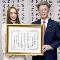 Pop singer Namie Amuro receives a certificate honoring her achievements from Okinawa Gov. Takeshi Onaga at a ceremony at the Okinawa Prefectural Government office in Naha on Wednesday. | KYODO