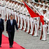 Chinese Premier Li Keqiang reviews the guard of honor with Prime Minister Shinzo Abe during a welcoming ceremony before their bilateral talks at Akasaka Palace state guest house in Tokyo on Wednesday. | REUTERS