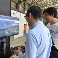 A man operates a single-copter flight simulator at a drone school in Koto Ward, Tokyo, on May 15. | YOSHIAKI MIURA