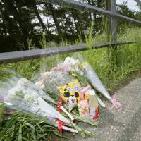 Bouquets, drinks and snacks line a roadside Friday along the rail line where elementary school student Tamaki Omomo was found dead in Niigata late Monday. | KYODO