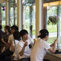 Customers eat ice cream at Niseko Milk Kobo in the town of Niseko, Hokkaido, in 2016. | BLOOMBERG