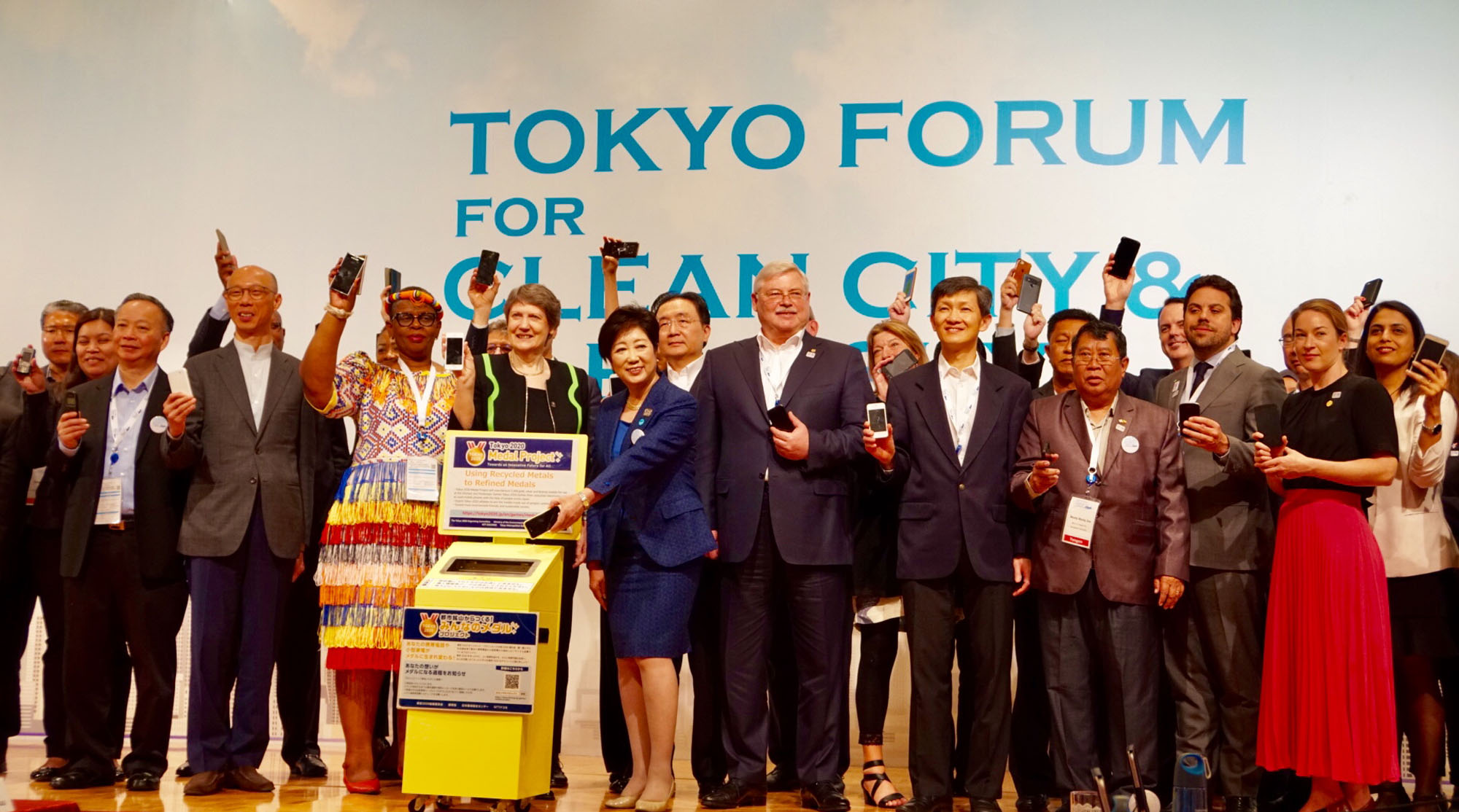 Joined by governors and mayors from global megacities, Tokyo Gov. Yuriko Koike (center) prepares to drop a used cell phone into a recycling collection box during a two-day symposium that concluded on Wednesday in Tokyo. | CHISATO TANAKA