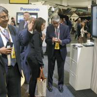 Visitors peruse Hitachi Ltd.\'s booth at an exhibition in New York on Wednesday focusing on next-generation energy technologies for urban areas that could increase efficiency and reduce traffic jams. | KYODO