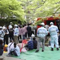 Firefighters look after people who evacuated from Nanzenji temple in Kyoto, where a pungent chemical smell forced about 70 visitors to evacuate Wednesday. | KYODO