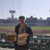 Andy Brown poses with his paintings during the National High School Baseball Tournament at Koshien Stadium last year. | COURTESY OF ANDY BROWN