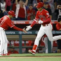 Shohei Ohtani is congratulated by Angels third base coach Dino Ebel after his home run during the ninth inning against the Rays on Thursday. | AP