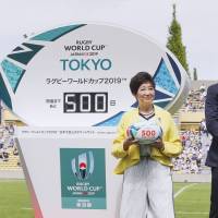 Rugby star Ayumu Goromaru (right) and Tokyo Governor Yuriko Koike (center) participate in an event marking 500 days to go until Rugby World Cup 2019 at Prince Chichibu Memorial Rugby Ground on Sunday. | KYODO