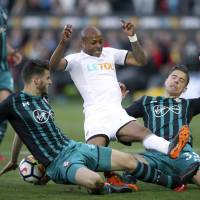 Southampton\'s Wesley Hoedt (left) and Jan Bednarek (right) tackle Swansea\'s Andre Ayew during their Premier League match in Swansea, Wales, on Tuesday. | AP