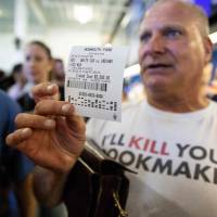 Professional odds-maker Stu Feiner holds up a betting slip for &#36;5,000 Thursday after placing a bet at the Monmouth Park Sports Book on the first day of legal sports betting in the state, in Monmouth, New Jersey. | AFP-JIJI