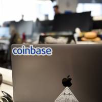 A Coinbase Inc. sticker is seen on a laptop computer at the company\'s office in San Francisco last Dec. 1. | BLOOMBERG