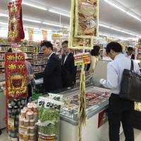 Customers check out a store jointly operated by FamilyMart and Don Quijote on Friday in the city of Tachikawa in western Tokyo. | KAZUAKI NAGATA