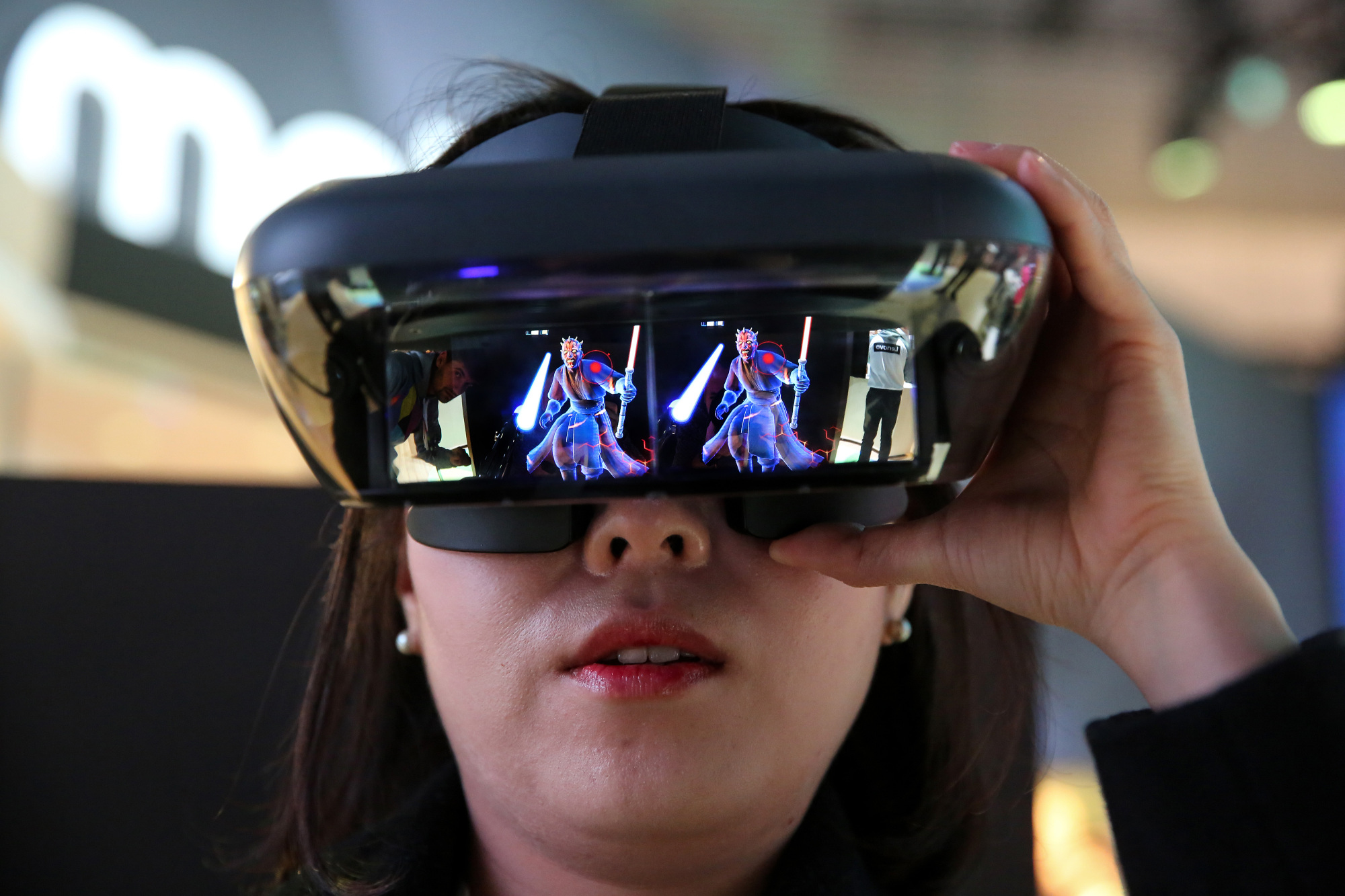 A woman plays the game 'Star Wars: Jedi Challenges' with a Lenovo augmented-reality headset at the Mobile World Congress in Barcelona, Spain, on Feb. 27. | BLOOMBERG