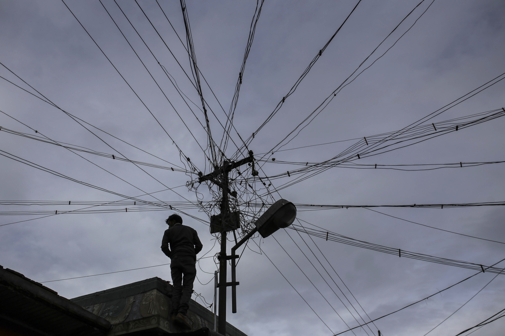 An electrician carries out work near a utility pole in Coonoor, in southern India's Tamil Nadu state, on June 7. | BLOOMBERG