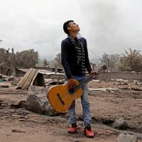 Brian Rivera, who lost 13 members of his family during the eruption of the Fuego volcano, holds his sister\'s guitar near debris of his home at San Miguel Los Lotes, Escuintla, Guatemala, Thursday. | REUTERS