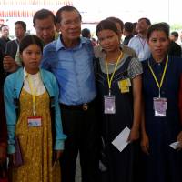 Cambodian Prime Minister Hun Sen poses with garment workers during a rally in Kandal province on May 30. | REUTERS