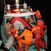 Indonesian personnel disembark from a rescue boat as it returns to harbor due to bad weather after a boat overturned in Lake Toba in the province of North Sumatra on Monday. | AFP-JIJI