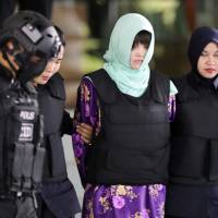 Vietnamese Doan Thi Huong, center, is escorted by police as she leaves the high court in Shah Alam, Malaysia, on June 28. Two Southeast Asian women on trial for killing the estranged half brother of North Korea\'s leader must have been trained in use of \"criminal force\" to rub the toxic VX nerve agent on Kim Jong Nam\'s eyes and face, prosecutors said Thursday. | AP