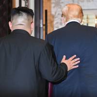 North Korean leader Kim Jong Un puts his hand on U.S. President Donald Trump\'s back as the pair leave a signing ceremony during their historic summit at the Capella Hotel on Singapore\'s Sentosa Island on Tuesday. | AFP-JIJI