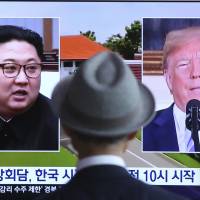A man watches a TV screen showing file footage of U.S. President Donald Trump and North Korean leader Kim Jong Un during a news program at the main railway station in Seoul on Monday, a day ahead of the two leader\'s historic summit in Singapore. | AP