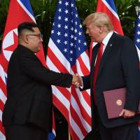 U.S. President Donald Trump and North Korea\'s leader Kim Jong Un shake hands during the signing of a document after their summit at the Capella Hotel on Sentosa island in Singapore on Tuesday. | REUTERS