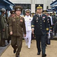 South Korean Maj. Gen. Kim Do-gyun (right) is escorted by a North Korean officer after crossing to North Korea for the meeting at the northern side of Panmunjom in the Demilitarized Zone on Friday. | SOUTH KOREA DEFENSE MINISTRY / VIA AP