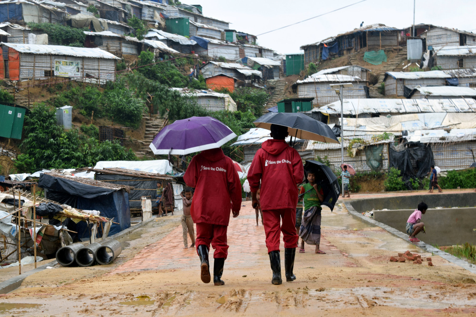 Save the Children representatives walk after a storm at the Chakmarkul refugee camp in Cox's Bazar, Bangladesh, on June 10. | REUTERS