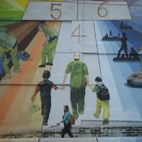 A woman walks past a mural titled \"Migration is not a game of hop scotch,\" painted by Salvadorian artist Rafael Moreira, on a residential building at the Monserrat neighborhood in San Salvador Thursday. For now the media ruckus and international outrage caused by the policy of separating children from their parents when they are detained illegally crossing the U.S. border is likely to deter more Central Americans from leaving home, said Andrew Selee, president of the Washington-based Migration Policy Institute. | AP