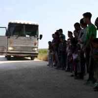 Immigrants who turned themselves in to border patrol agents after illegally crossing the border from Mexico into the U.S. wait to be transported for processing in the Rio Grande Valley sector, near McAllen, Texas, on April 2. | REUTERS