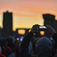People take photos as the sun rises at Stonehenge, in Wiltshire, England, where police estimate over 9,000 people gathered to celebrate the dawn of the longest day on June 21, 2018. The Neolithic monument is built along the solstice alignment of the summer sunrise and the winter sunset. | AP