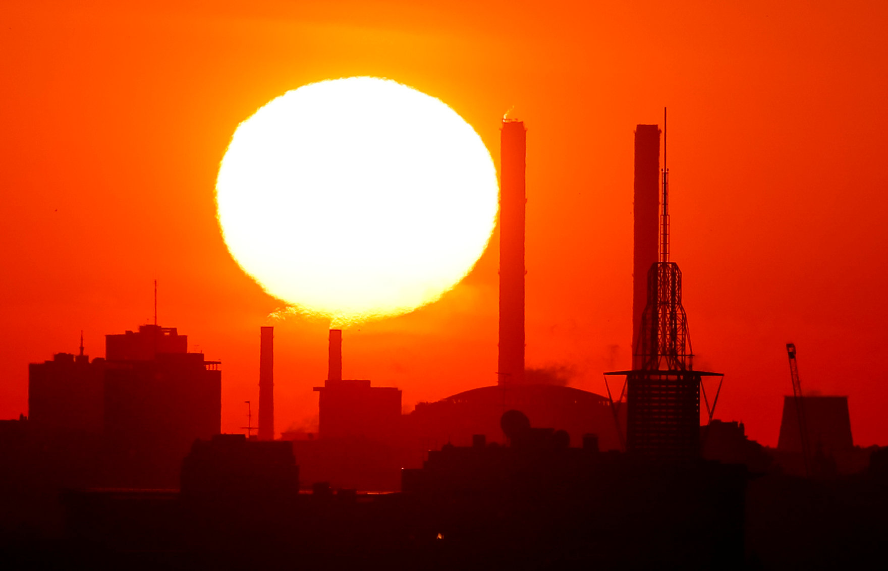 The sun rises behind chimneys of a power plant in Moscow in May. Over 200 million people in cities across the globe face stifling heat within the next three decades, researchers have warned. | REUTERS