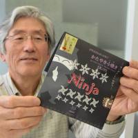Makoto Hisamatsu holds up a bag of cookies inspired by preserved snacks carried by ninja. | CHUNICHI SHIMBUN