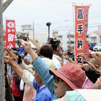 Residents gather in front of U.S. Kadena Air Base in Okinawa Prefecture on Monday to protest the temporary deployment of F-22 stealth fighter jets to the base. | KYODO