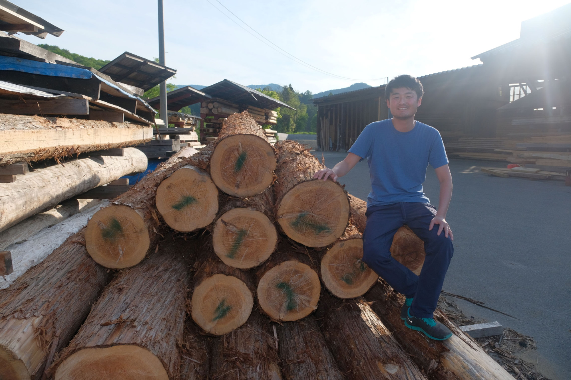 Shun Matsuzawa, an executive of a nonprofit organization that promotes local timber, poses with lumber in the town of Minamiaizu, Fukushima Prefecture. Logs marked in green are certified as environment friendly. | FUKUSHIMA MINPO