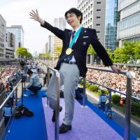 Figure skating superstar Yuzuru Hanyu waves to the crowd during a victory parade in Sendai in April. | KYODO