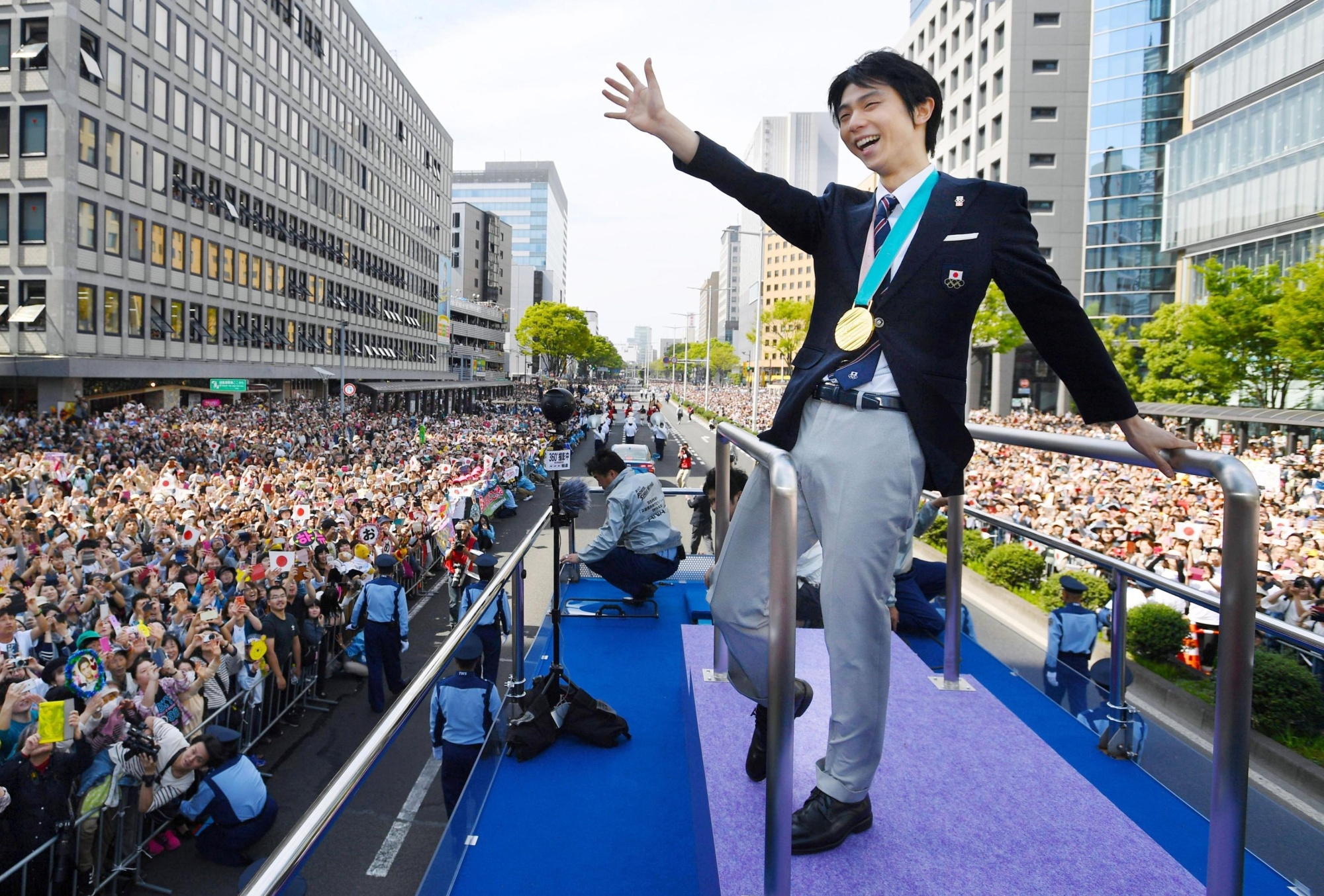 Figure skating superstar Yuzuru Hanyu waves to the crowd during a victory parade in Sendai in April. | KYODO