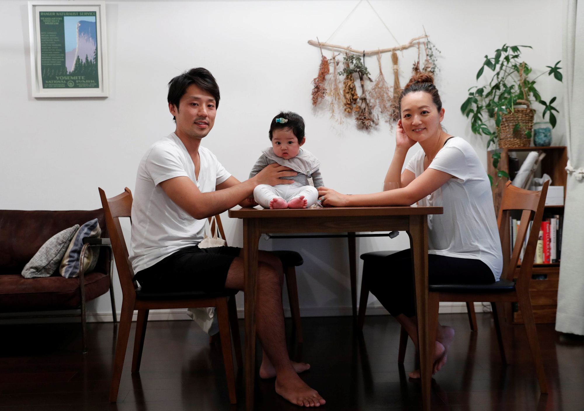 Eri Sato (right) poses with her husband, Tatsuya, and 3-month-old daughter, Sara, at their home in Yokohama on May 23. | REUTERS