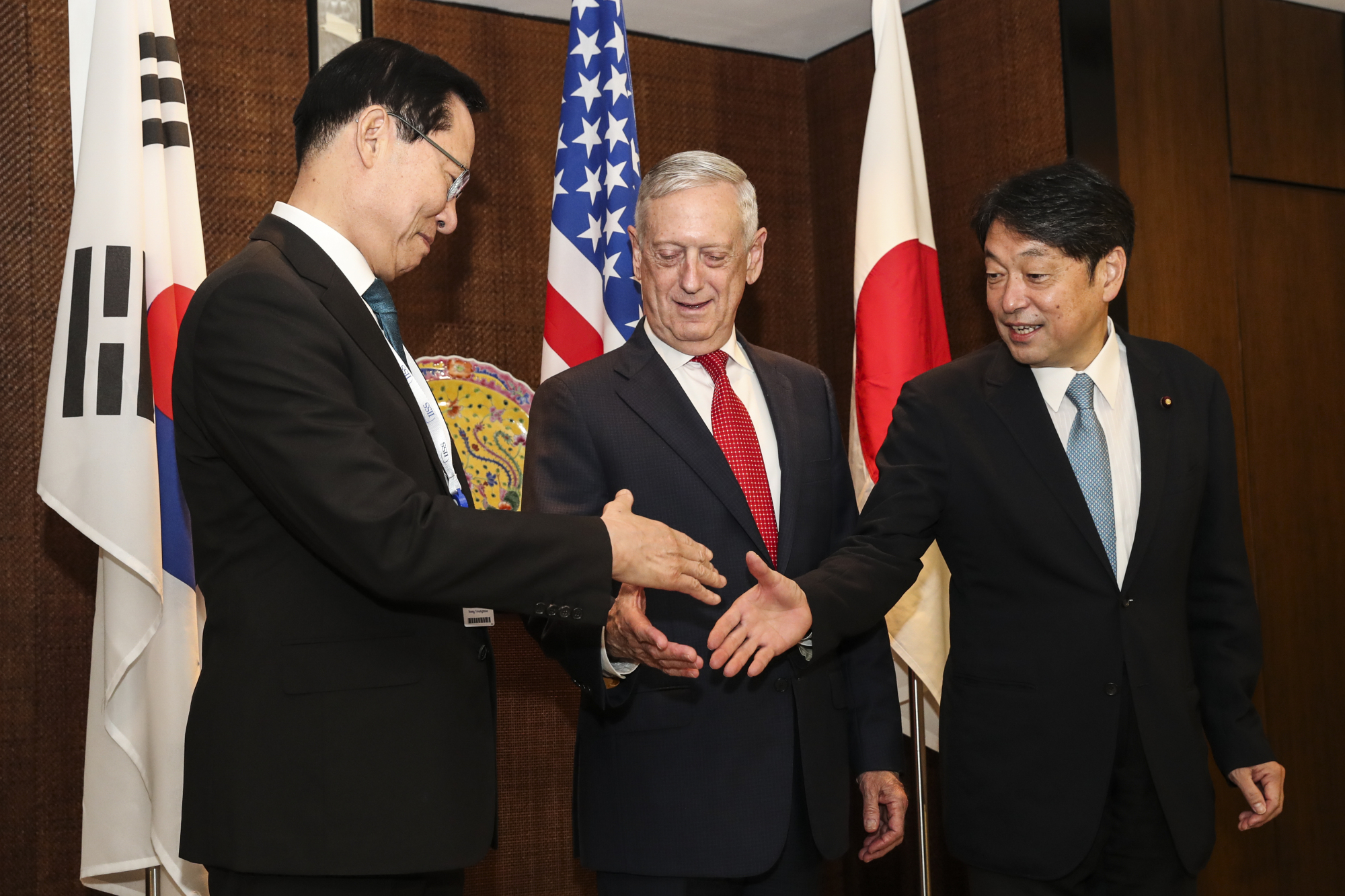South Korean Defense Minister Song Young-moo (left), U.S. Defense Secretary Jim Mattis and Defense Minister Itsunori Onodera shake hands before their trilateral meeting at the Shangri-la Dialogue in Singapore on Sunday. | AP