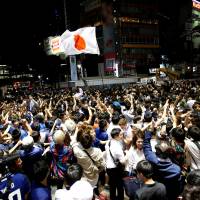 Soccer fans cheer near the scramble crossing in Tokyo\'s Shibuya district Monday following the Group H World Cup soccer match between Japan and Senegal in Russia. | REUTERS