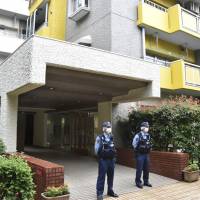 Police officers on Thursday stand in front of a Yokohama apartment building where a man reportedly slashed three people and fled earlier in the day, killing one. | KYODO
